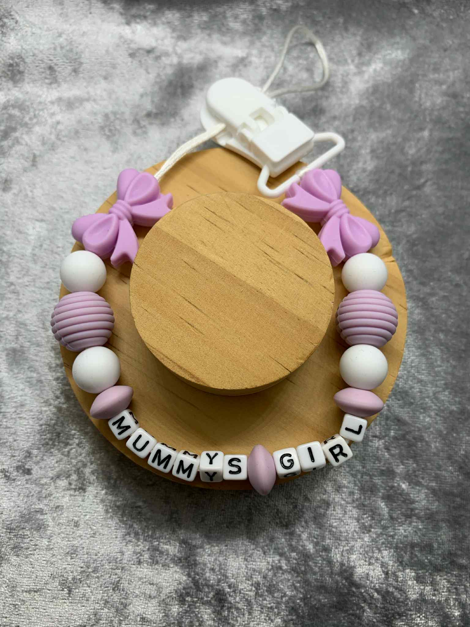 lilac dummy clip with bow with beads and 'Mummy's Girl' text on a gray background