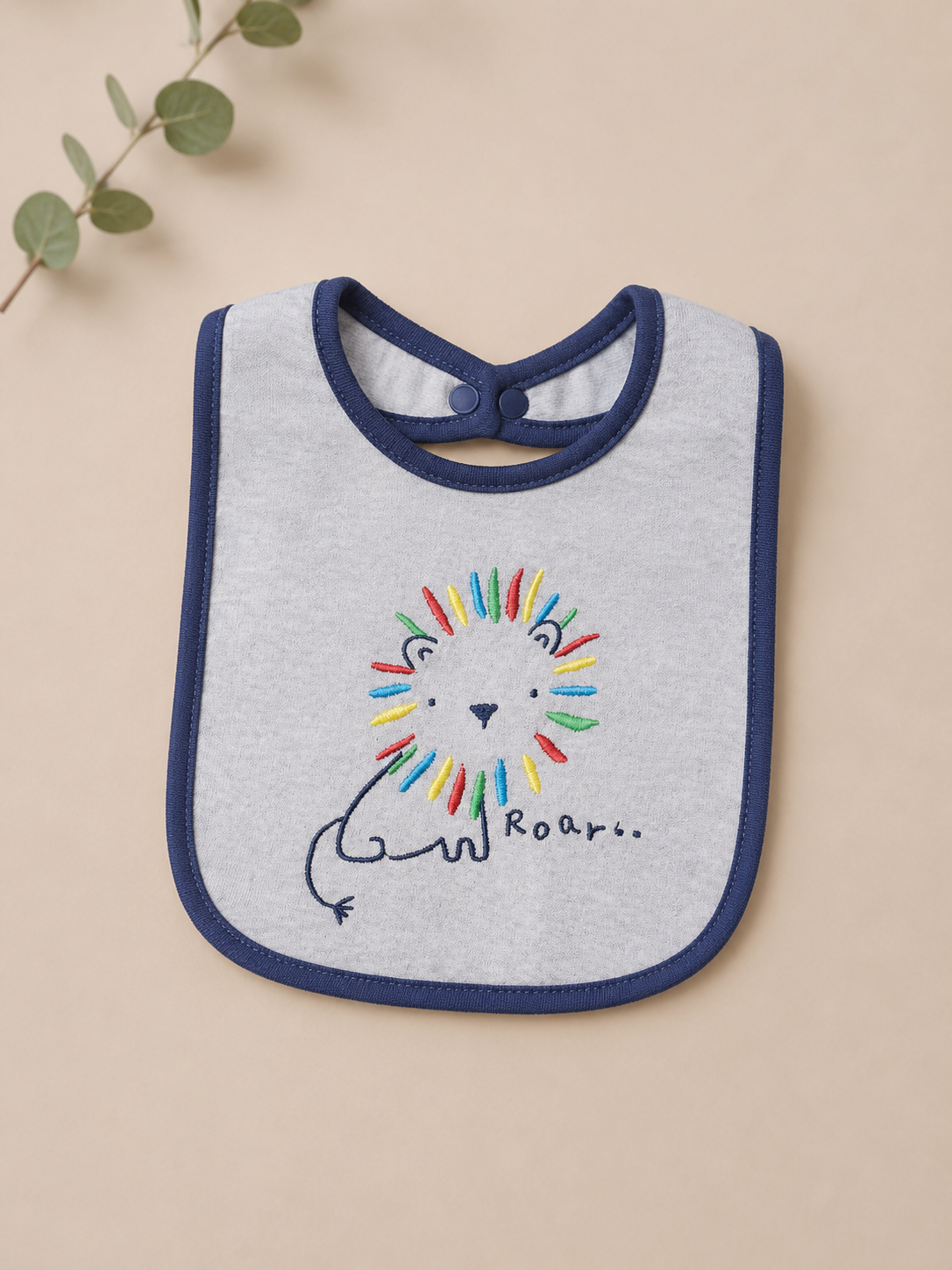 Baby bib with colorful lion design and 'Roar' text on a beige background
