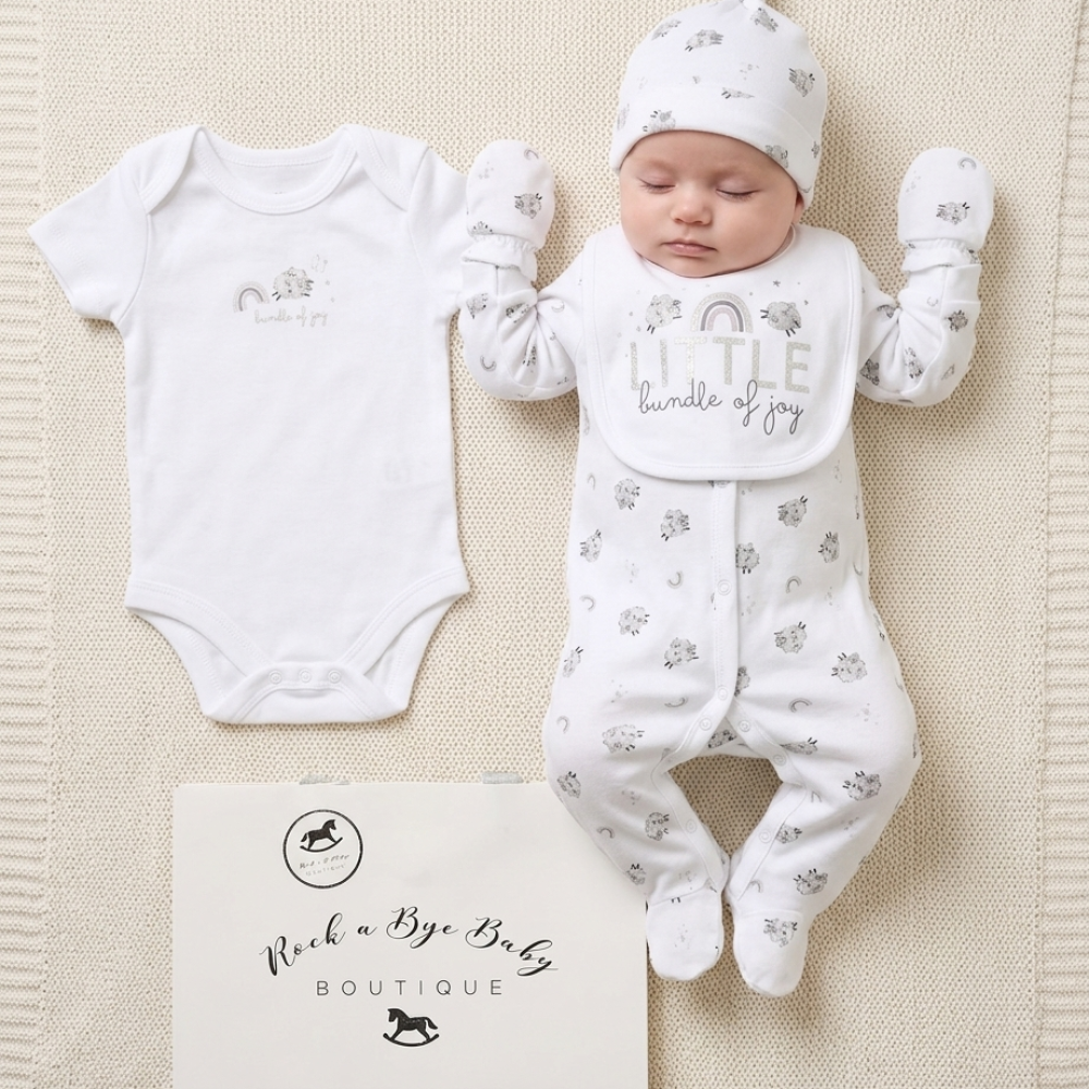 Baby outfit set with onesie, romper, and hat on a textured surface with 'Rock a Bye Baby Boutique' branding.