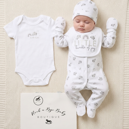 Baby outfit set with onesie, romper, and hat on a textured surface with 'Rock a Bye Baby Boutique' branding.