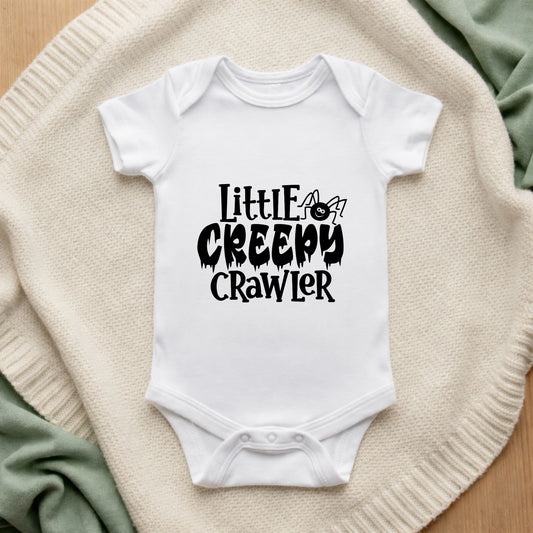 White baby onesie with 'Little Creepy Crawler' text on a textured surface