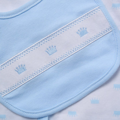 Close-up of a baby bib in light blue and white, featuring embroidered crown motifs and decorative stitching.