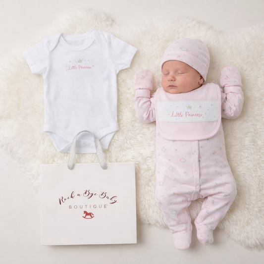 Baby girl's pink and white outfit with 'Little Princess' text, lying next to a baby bag on a soft surface.