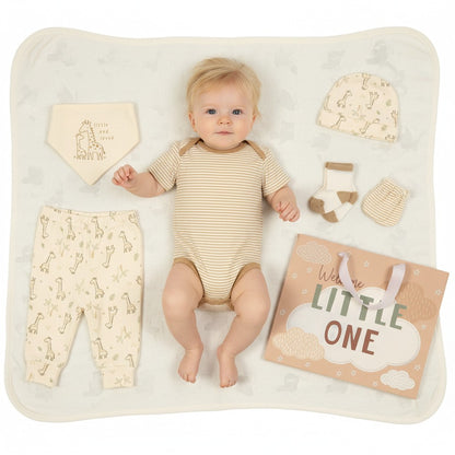 Baby lying on a white blanket with baby clothing and accessories around