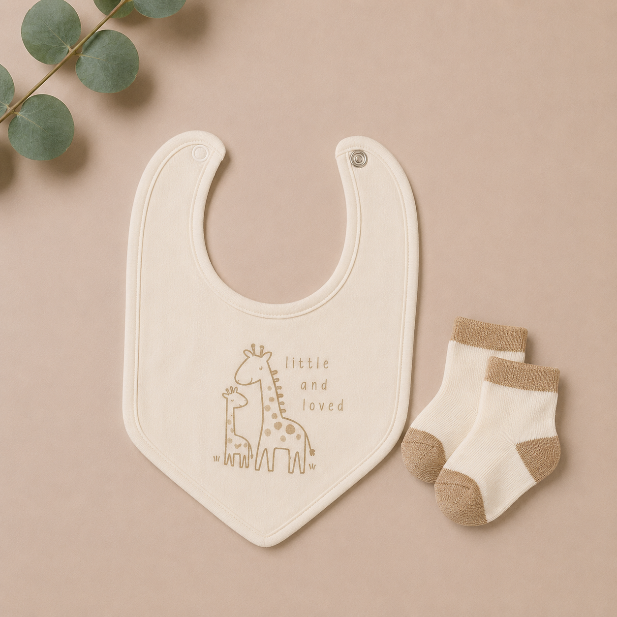 Baby bib with giraffe illustration and socks on a beige background