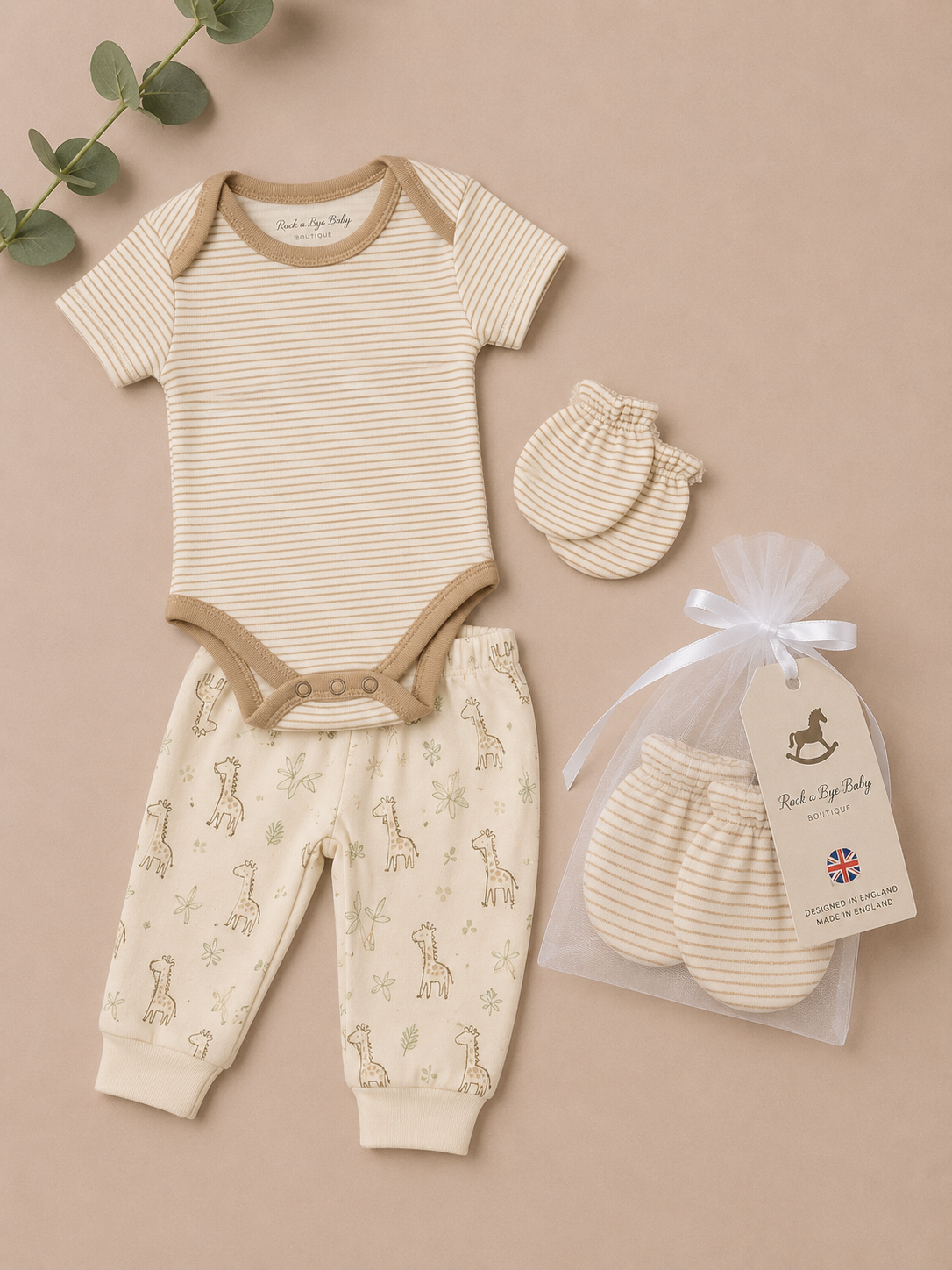 Baby clothing set with onesie, pants, and mittens on a beige background