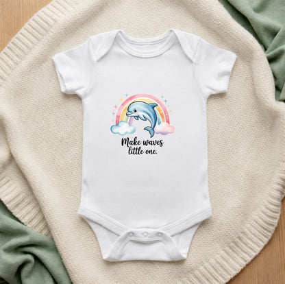 White baby onesie with a dolphin and rainbow design on a textured surface