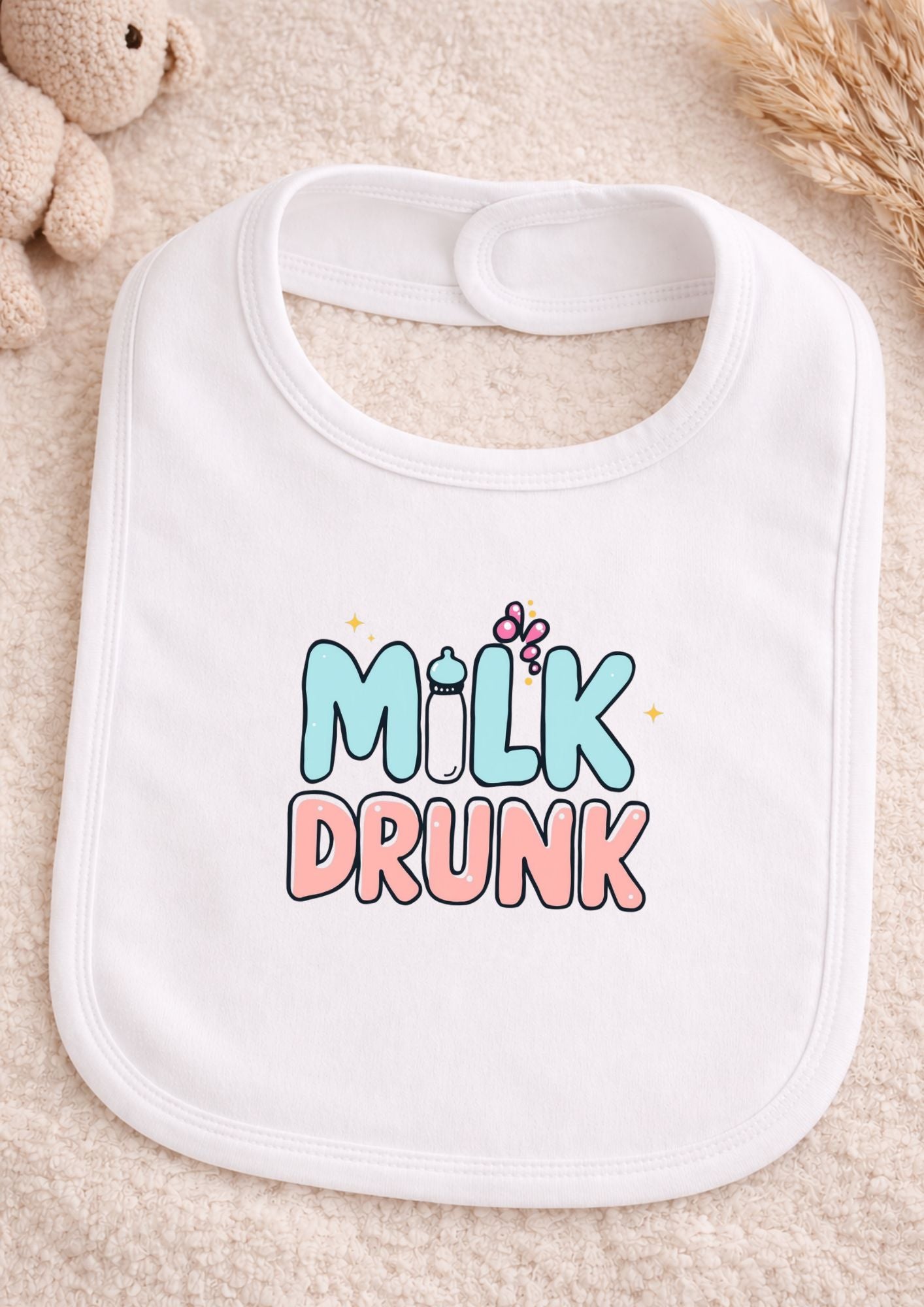 Baby bib with 'Milk Drunk' text on a soft surface