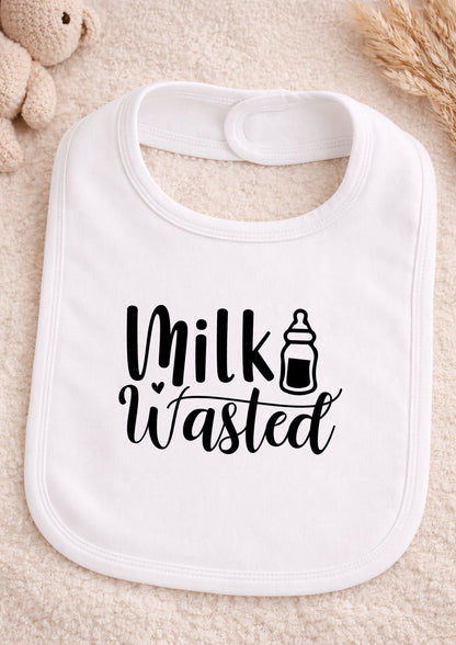 White baby bib with 'Milk Wasted' text and bottle icon on a beige surface