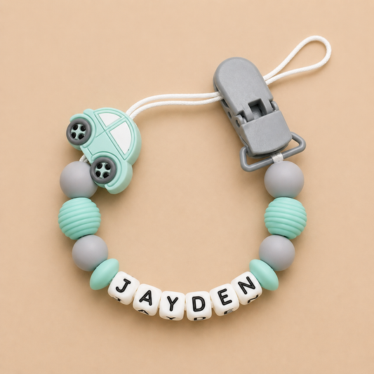 dummy clip with car-shaped clip and 'JAYDEN' name on a beige background