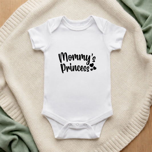 White baby onesie with 'Mommy's Princess' text on a textured surface