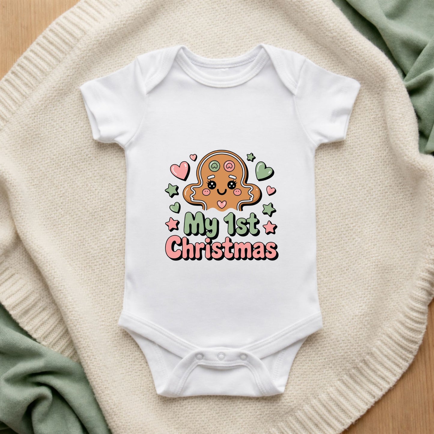 White baby onesie with a gingerbread design and 'My 1st Christmas' text on a textured surface.