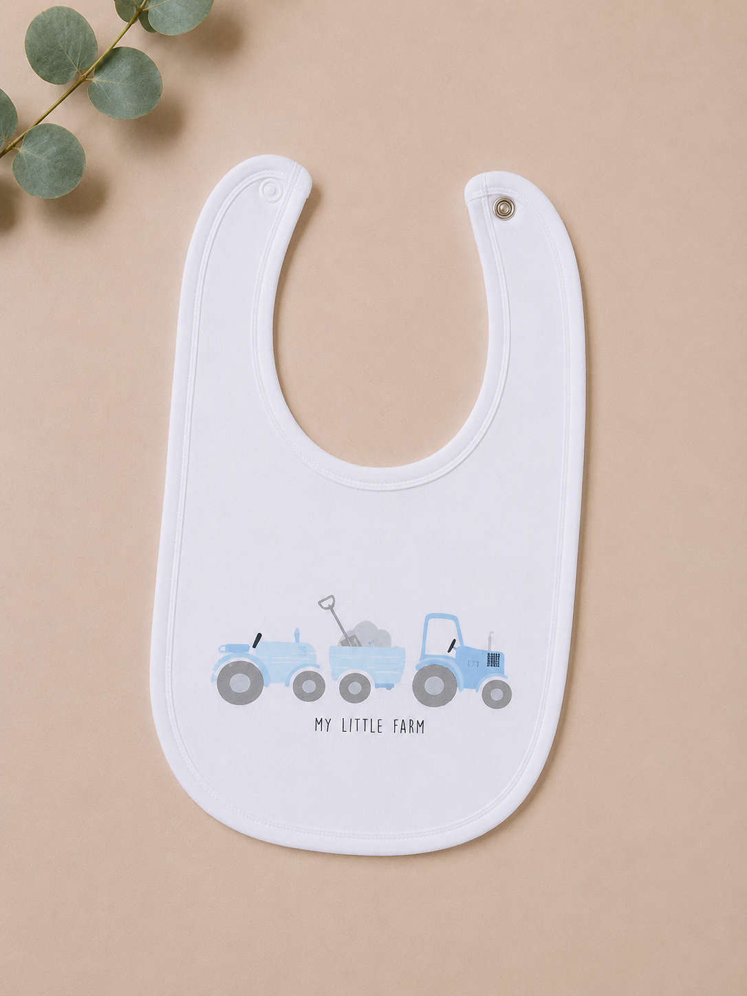 White bib with blue tractor design on a beige background