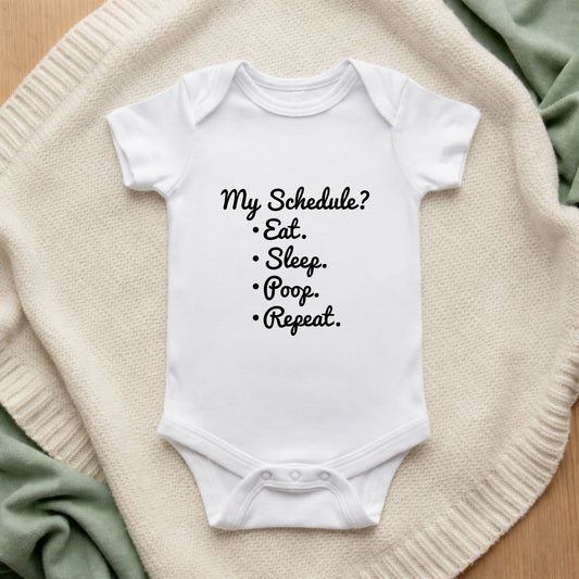 White baby onesie with humorous text on a soft surface My Schedule Eat Sleep  Poop Repeat Baby Bodysuit