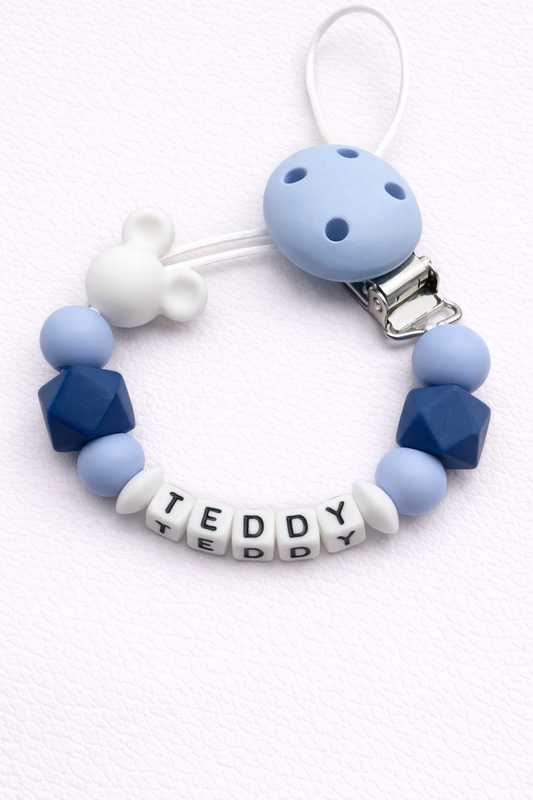 Blue and white dummy clip with 'TEDDY' letter beads on a white background