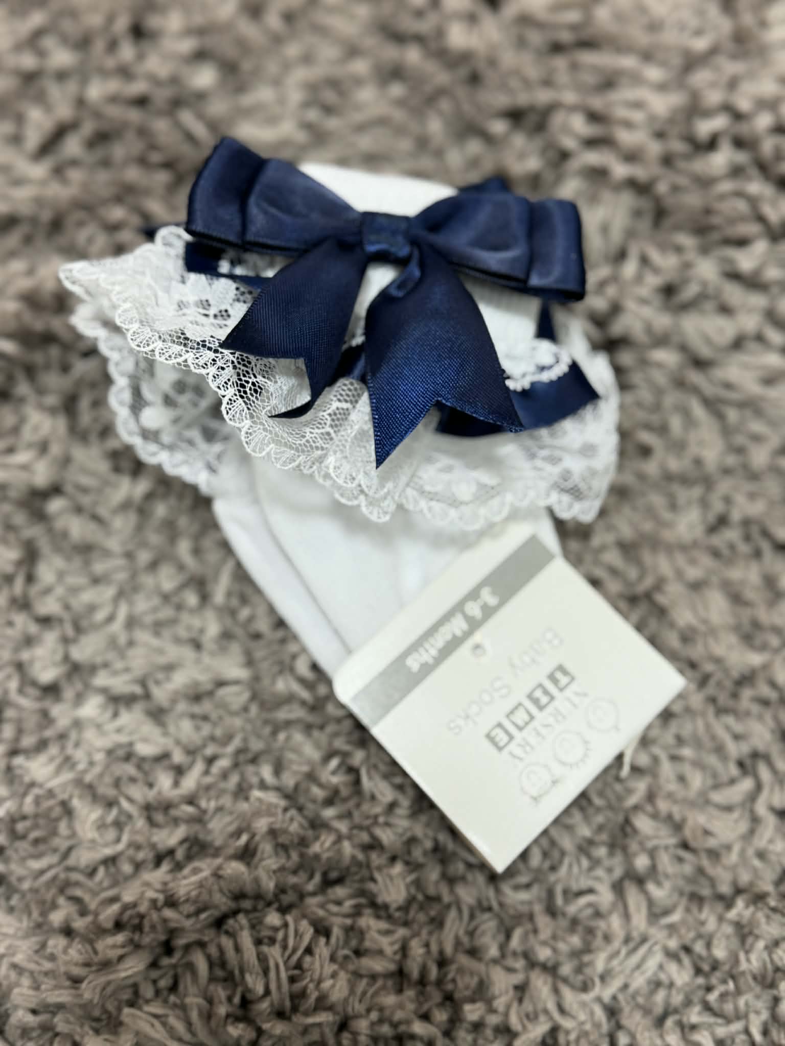 White socks with navy blue bow and lace details on a brown textured surface