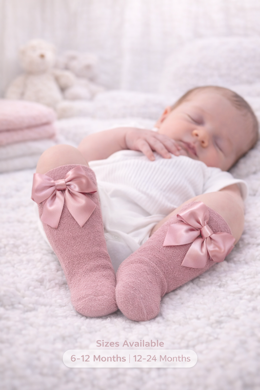 Cozy newborn baby wearing dusty pink knee-high socks on plush bedding