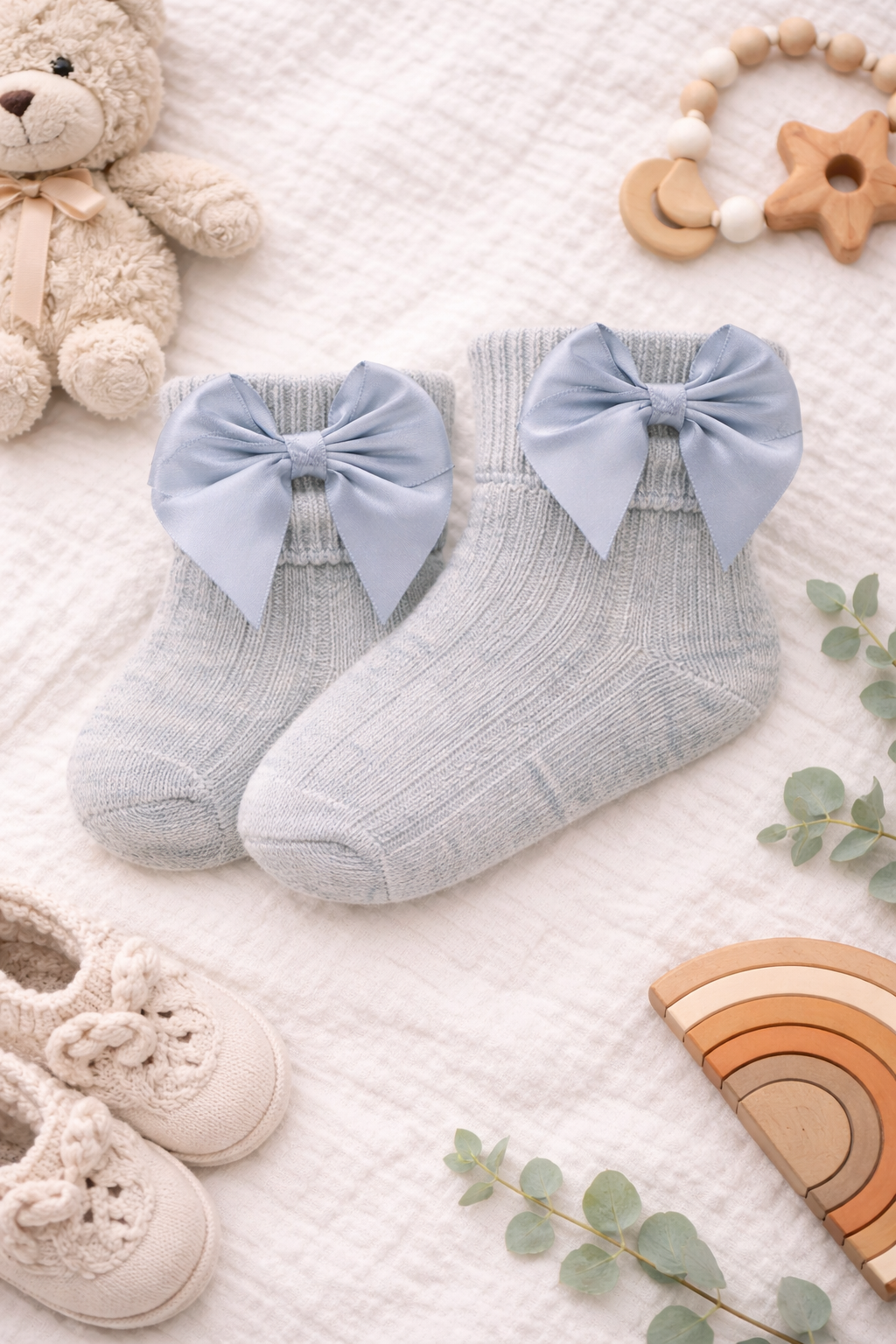 Close-up mockup of a newborn baby wearing grey baby socks with delicate bow detail, paired with a white bodysuit and neutral nursery accessories.