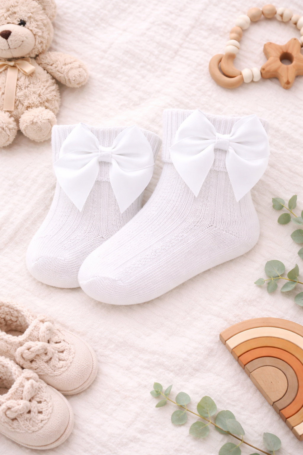 Lifestyle image of a newborn baby resting on a plush blanket, dressed in classic white baby socks finished with elegant satin bows, ideal for christenings, photoshoots, and special occasions.