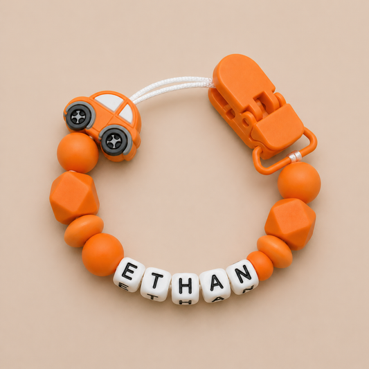 Orange dummy clip with car design and 'ETHAN' name beads on a beige background