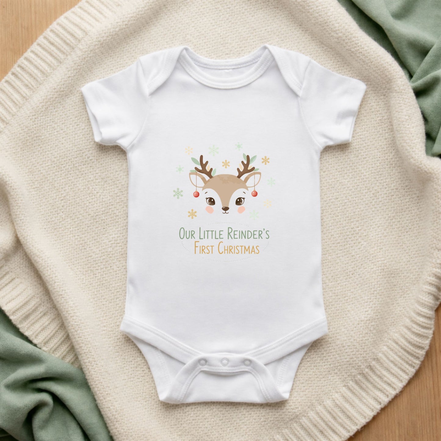 Baby onesie with reindeer design and text on a soft surface