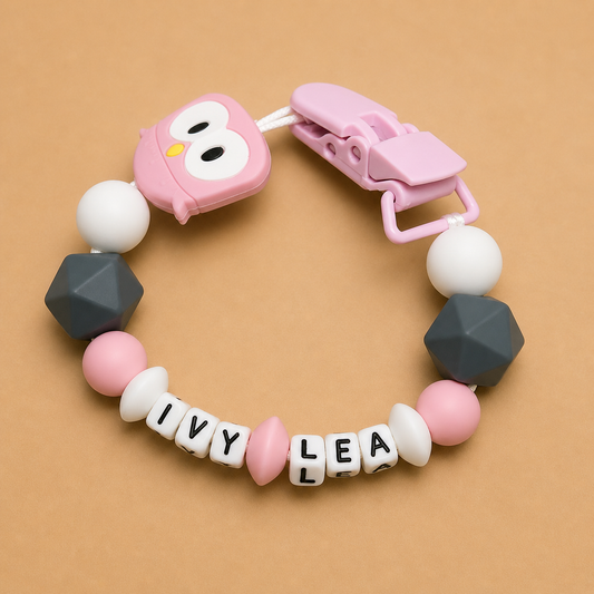 Baby teether with geometric beads and a pink clip on a beige background