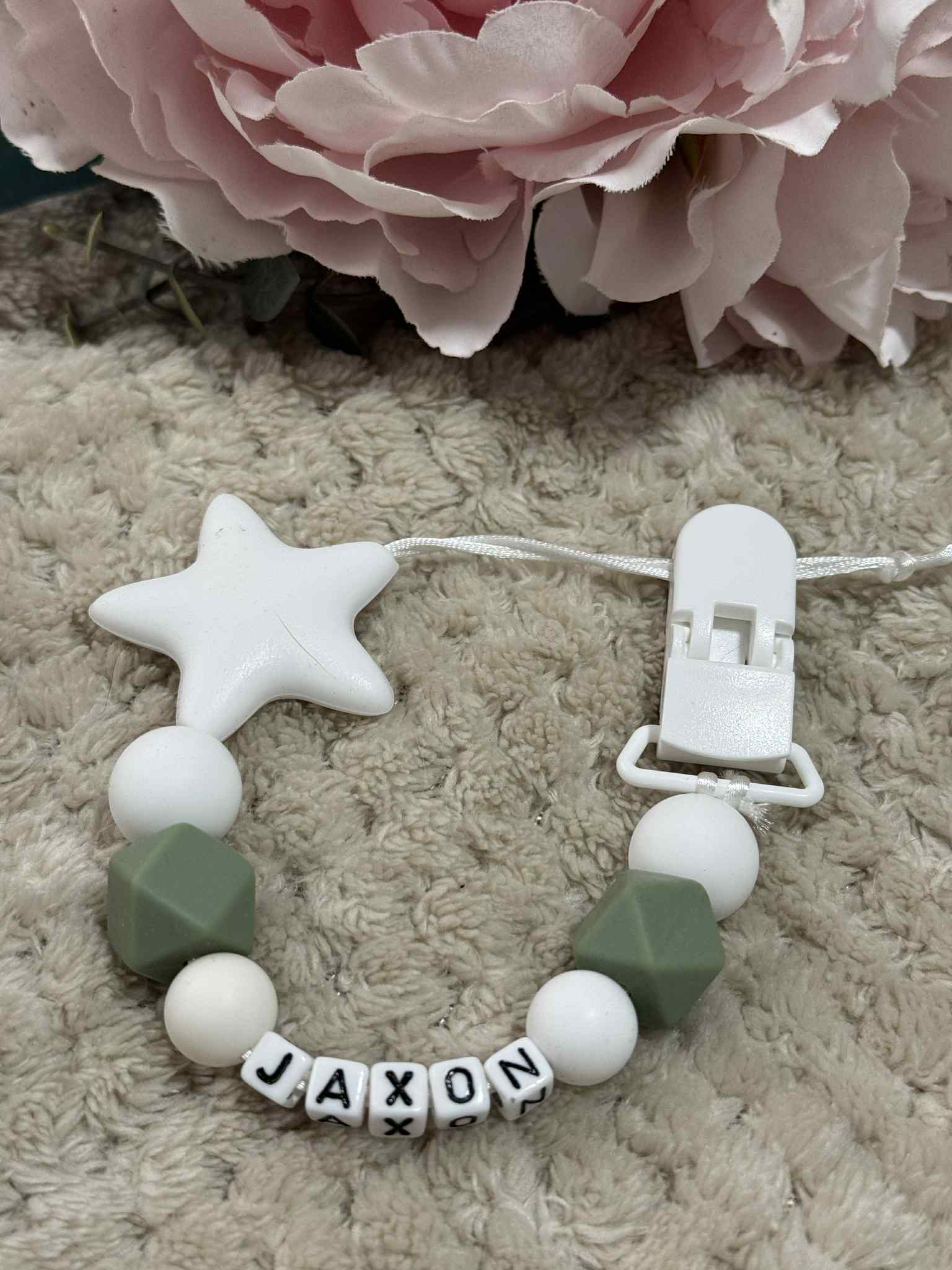 Green And white silicone dummy clip on a beige textured surface. Personalisation options available