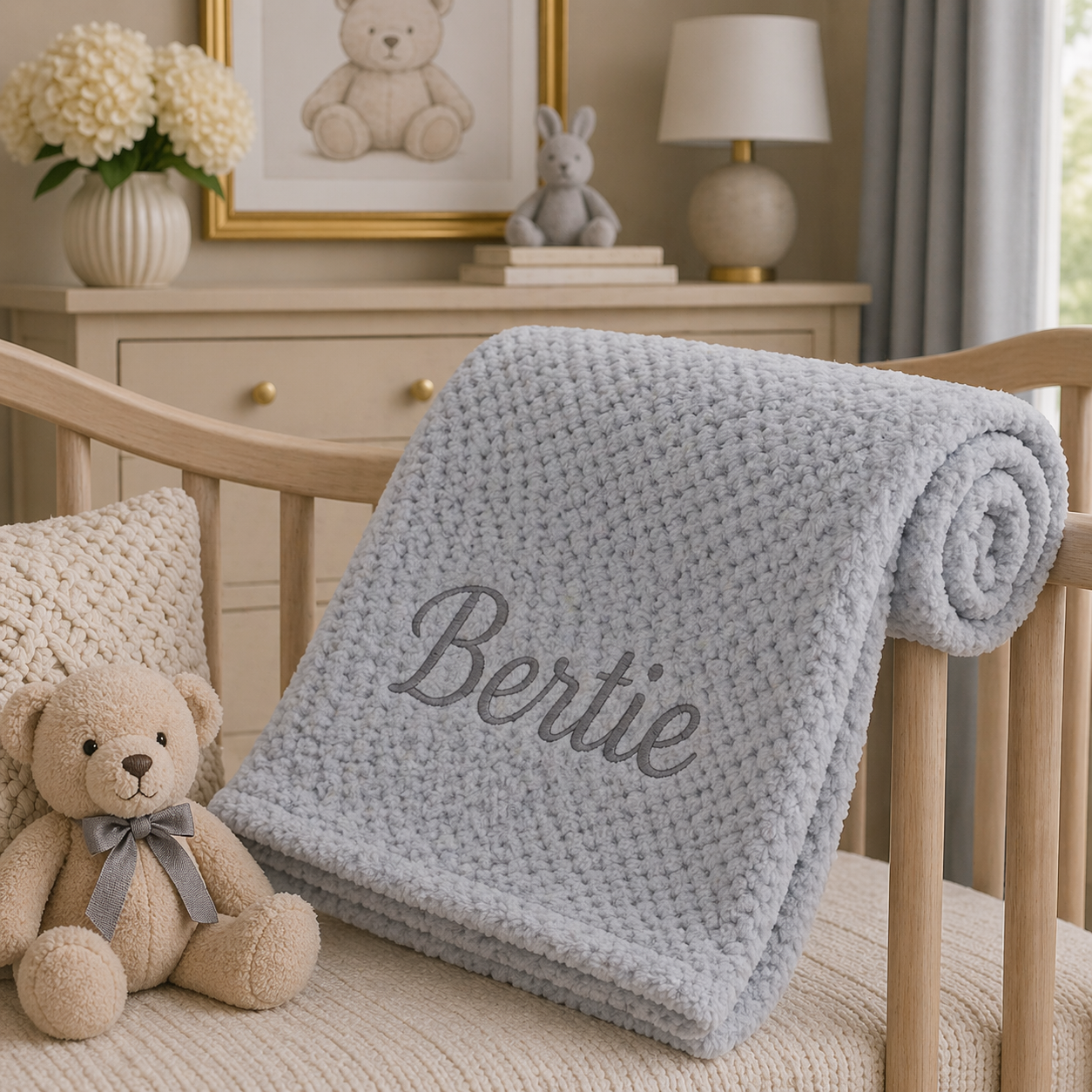 Gray blanket with 'Bertie' embroidered on a wooden crib in a nursery setting.