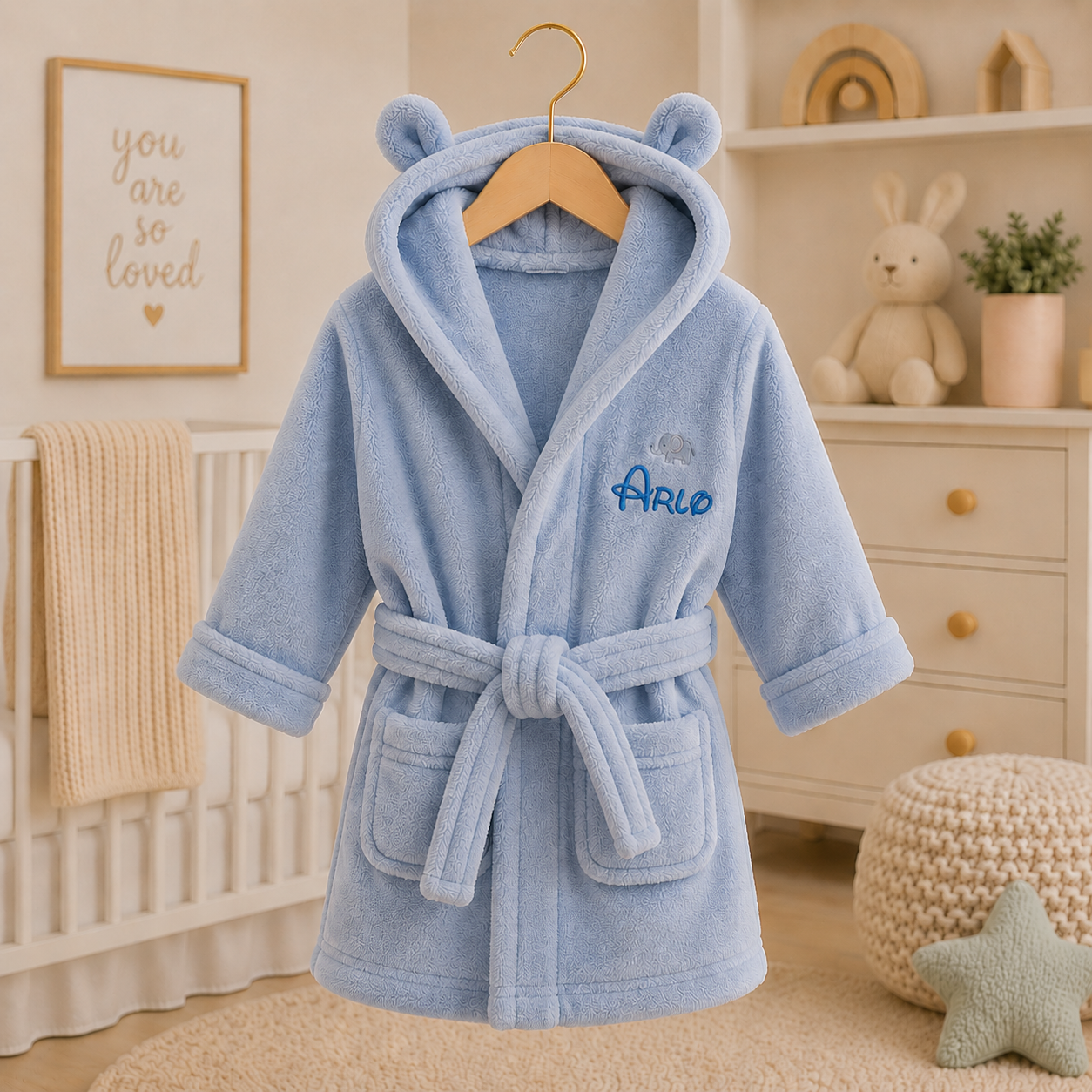 Blue children's robe with bear ears on a hanger in a nursery setting