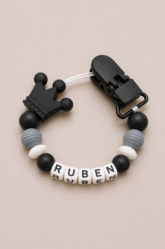 Black and gray beaded pacifier clip with 'Ruben' on a beige background