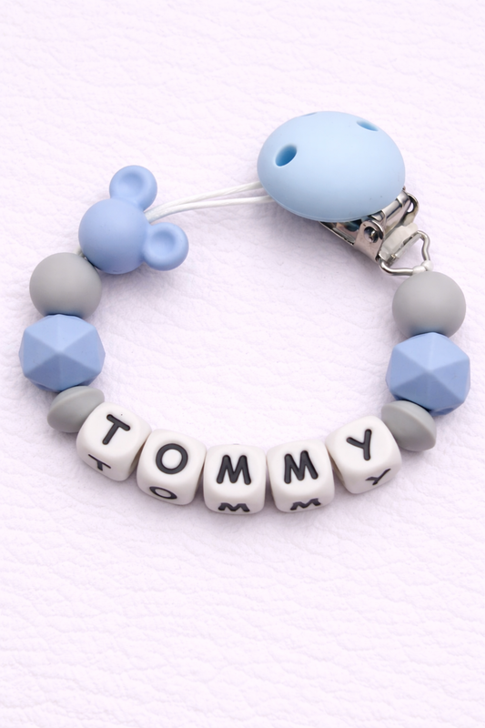 Baby dummy clip with name 'Tommy' on a white background