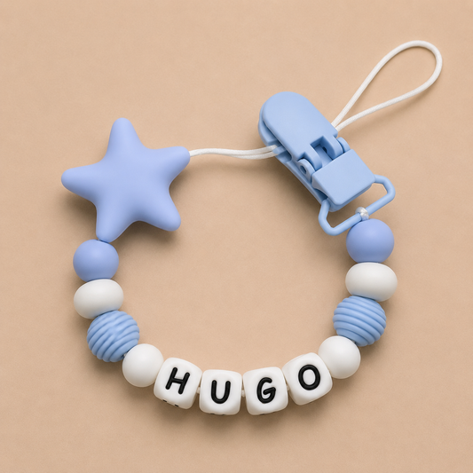 Baby dummy clip with star-shaped chewable component and 'HUGO' letter beads on a beige background