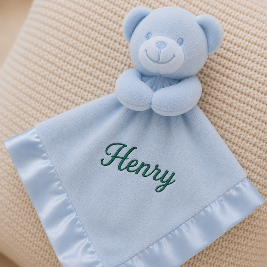 Blue teddy bear security blanket with 'Henry' embroidered on a beige textured background
