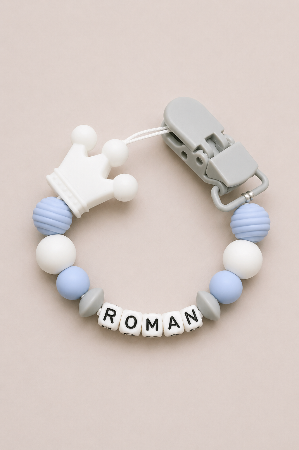 Teething ring with colorful beads and a clip on a beige background