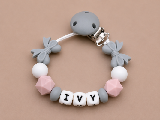 Silicone dummy clip with colorful beads and 'IVY' letters on a beige background