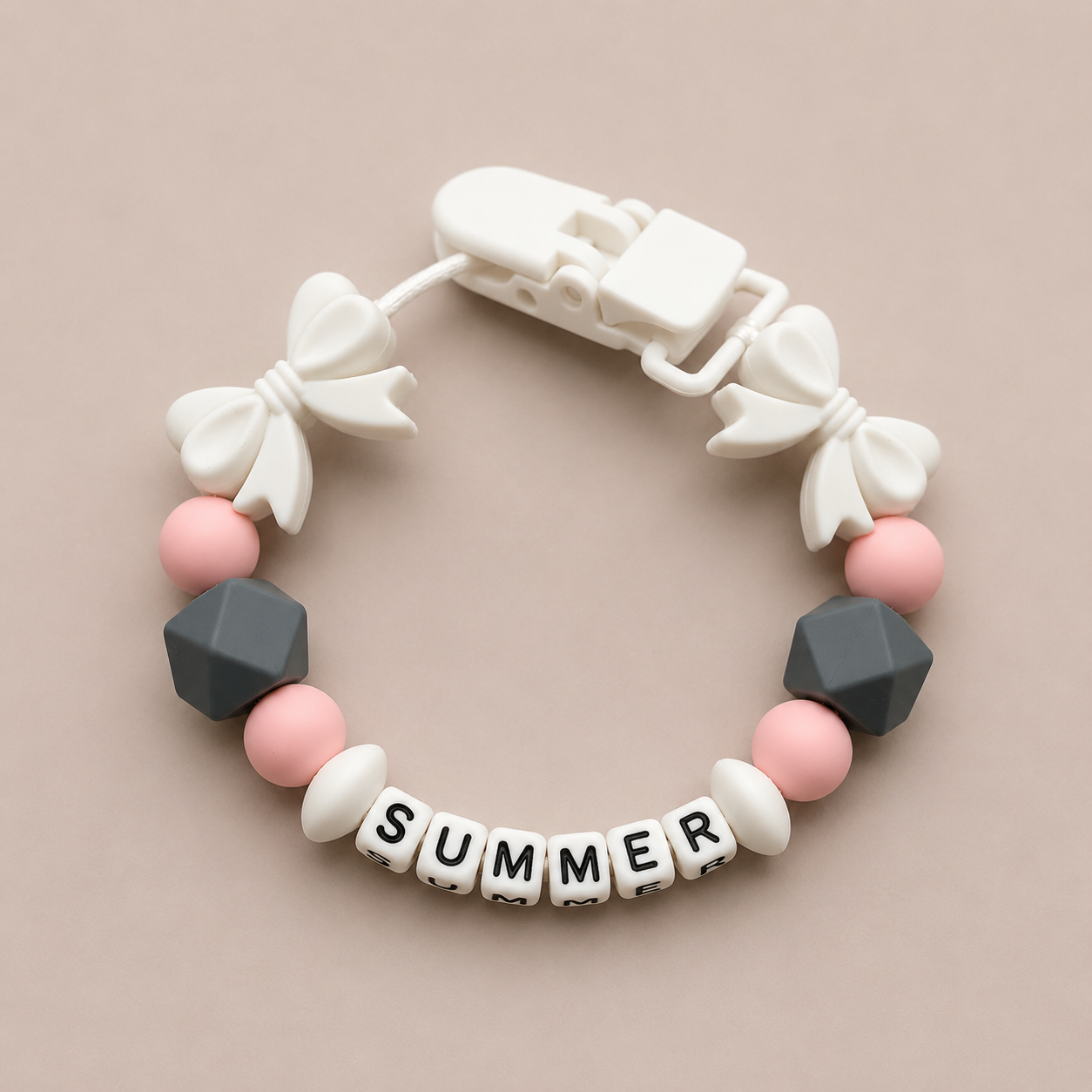 dummy clip with white bows, pink and gray beads, and 'SUMMER' letter beads on a beige background
