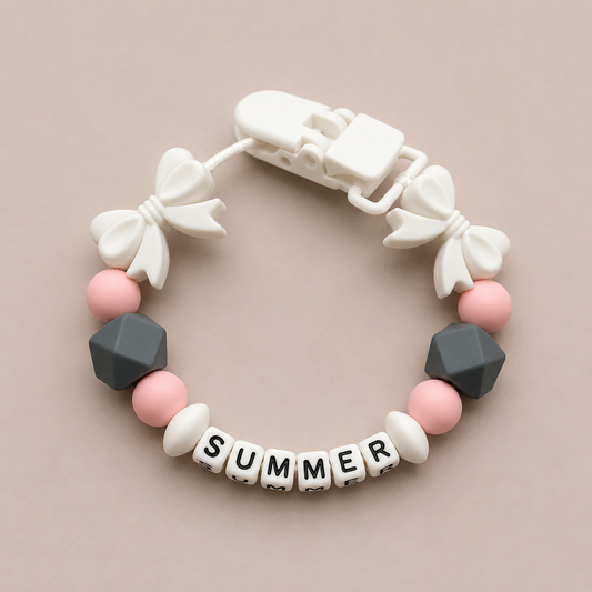 dummy clip with white bows, pink and gray beads, and 'SUMMER' letter beads on a beige background