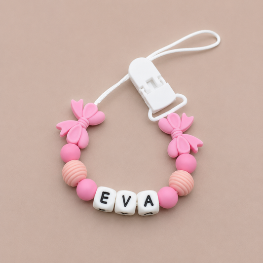 Pink and white dummy clip with 'EVA' beads on a beige background