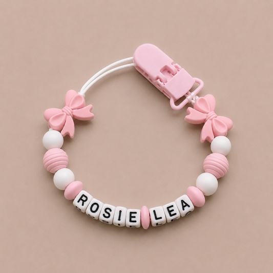 Pink and white dummy clip with 'ROSIE LEA' on a beige background