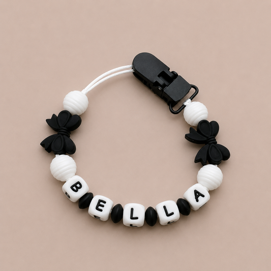 dummy clip with black, white, and black bow designs on a beige background