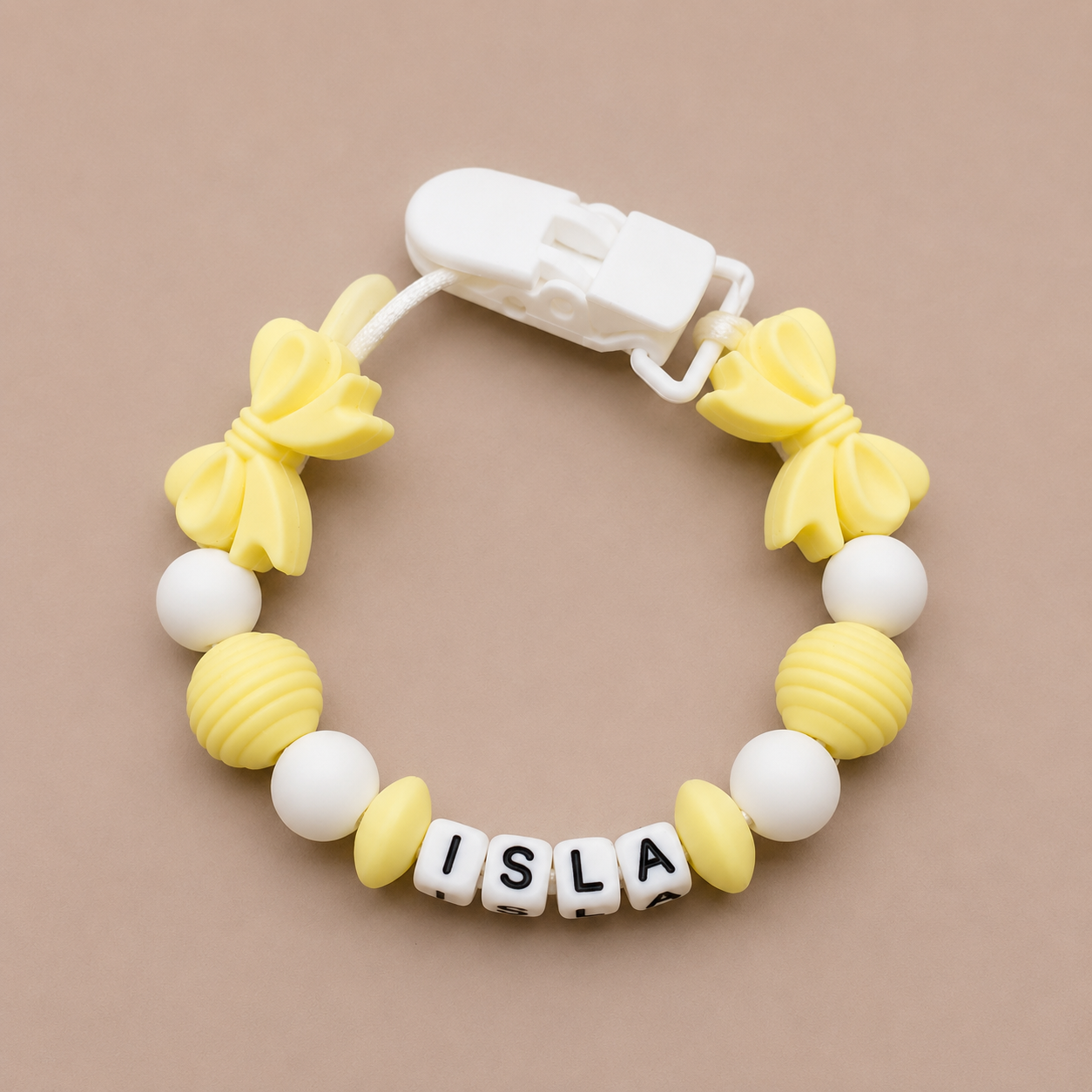 Yellow and white Dummy Clip with 'ISLA' on a beige background