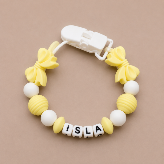 Yellow and white Dummy Clip with 'ISLA' on a beige background