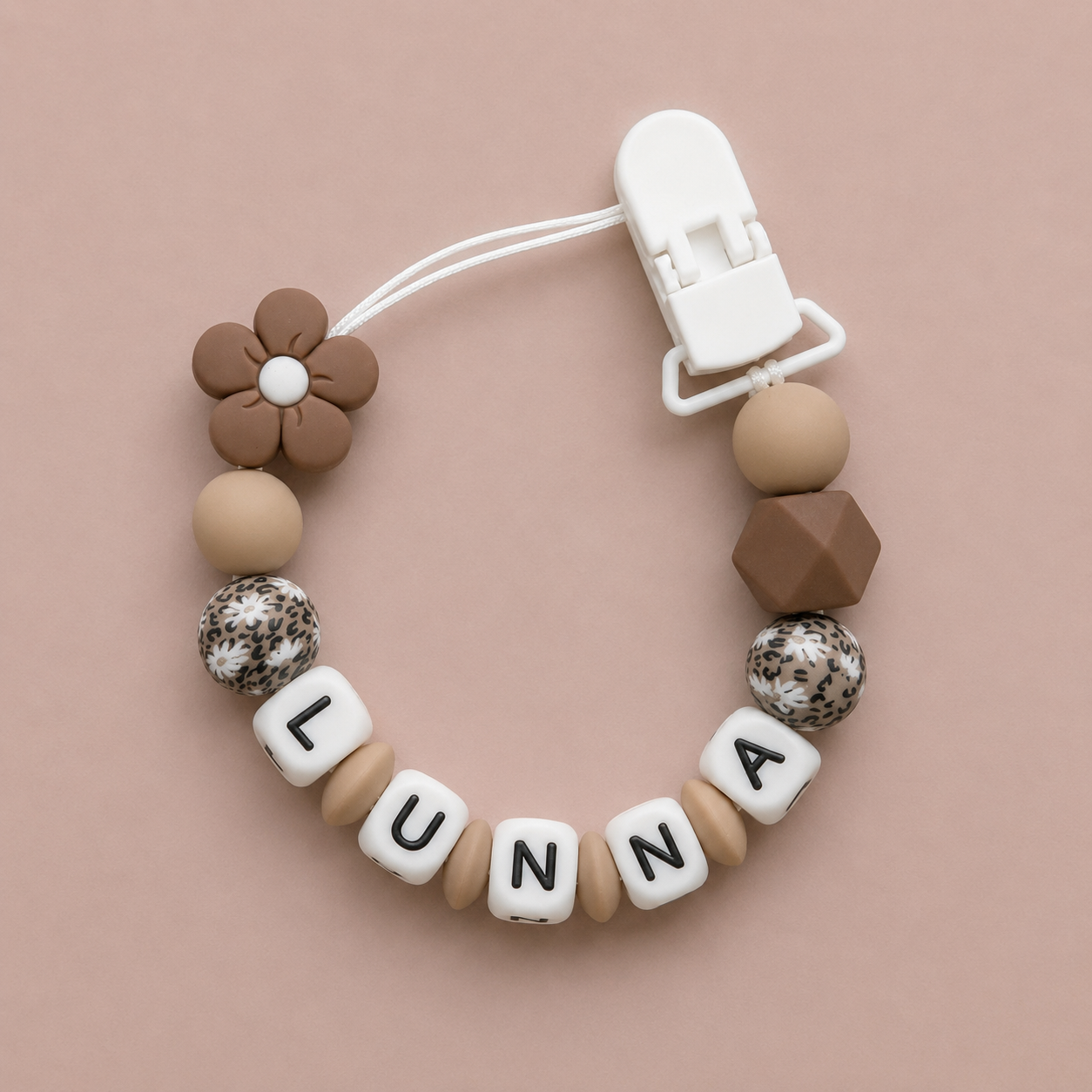 dummy clip with letter beads spelling 'LUNA' on a beige background