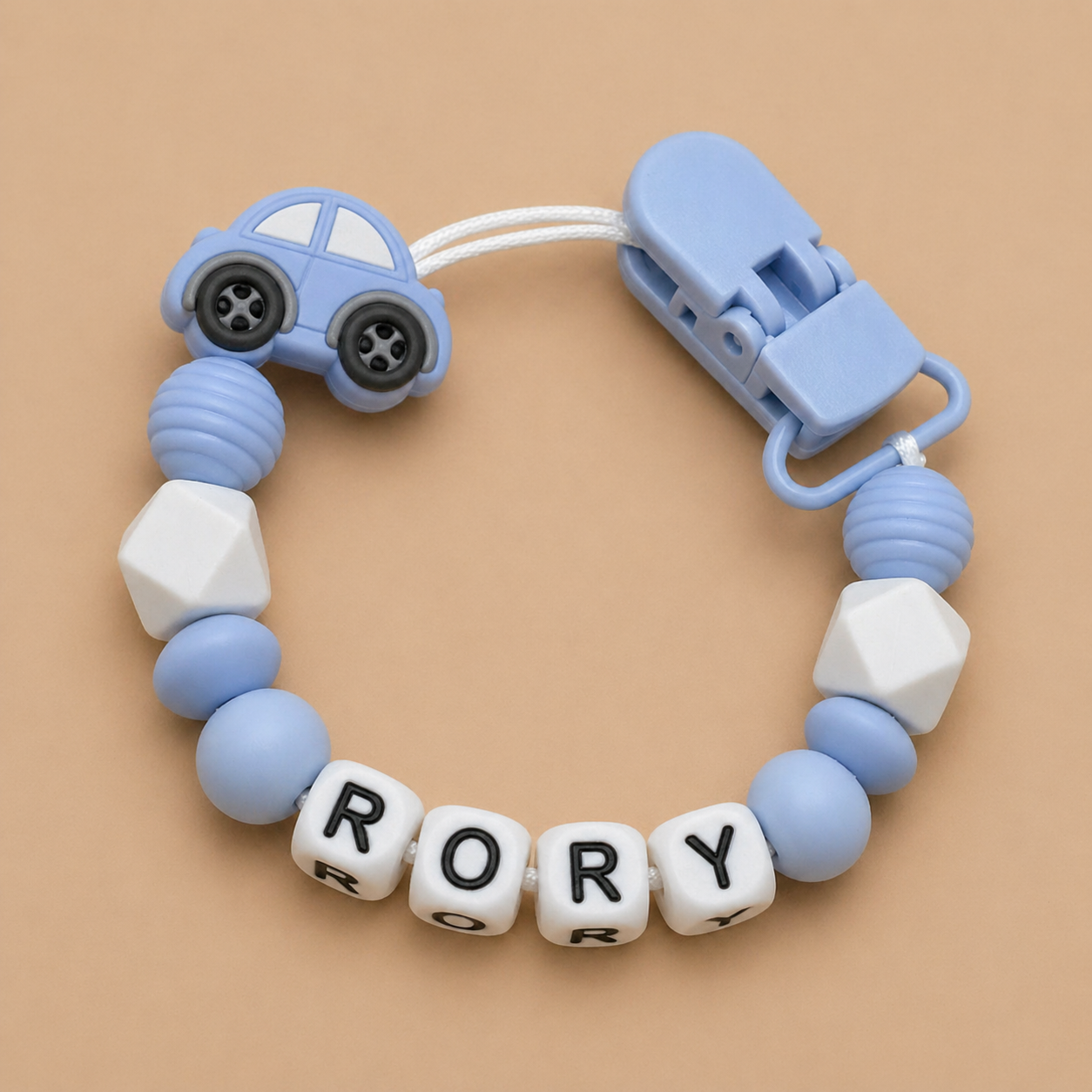 Baby teether with car design and 'RORY' beads on a beige background