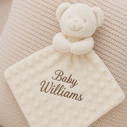 White teddy bear security blanket with 'Baby Williams' embroidery on a beige textured background
