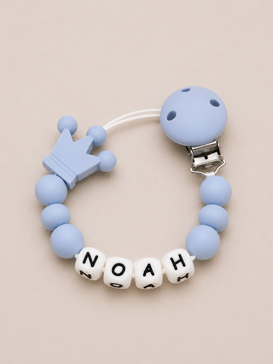 Blue baby teether with 'NOAH' name beads on a beige background