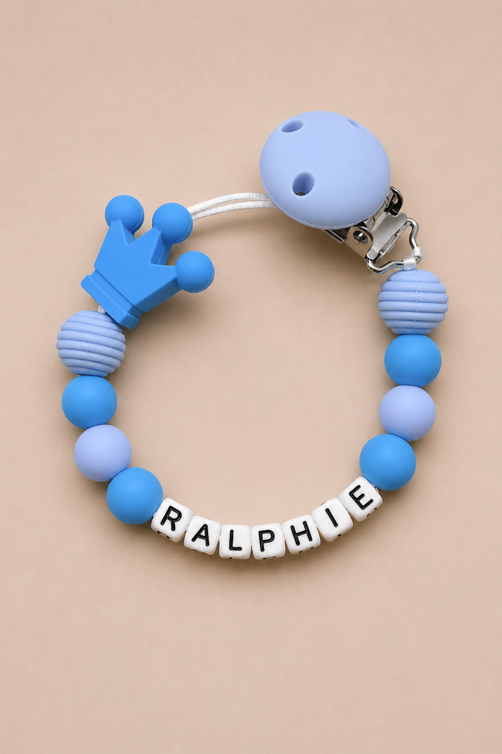 Blue teething ring with 'RALPHIE' on a beige background