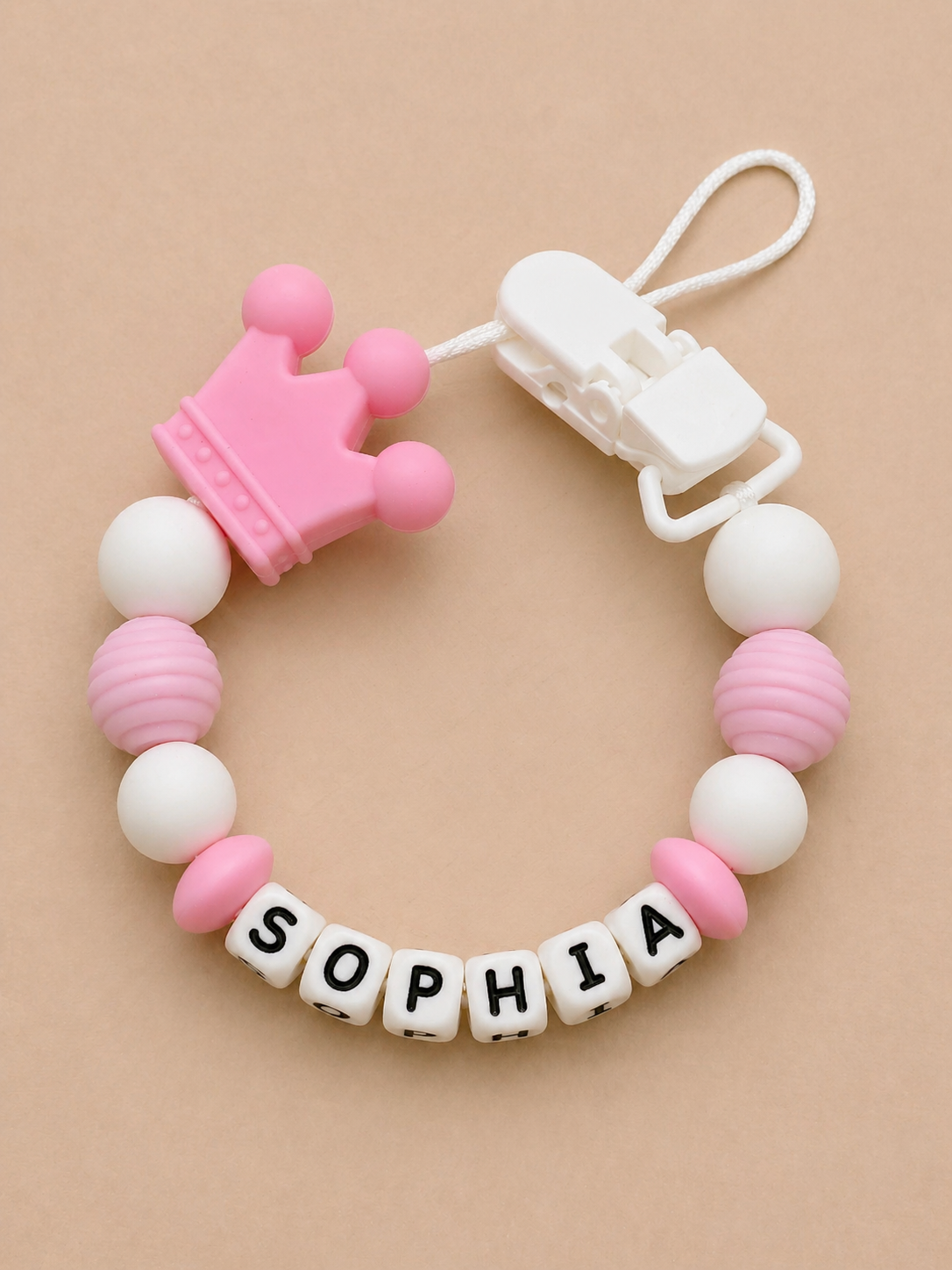 Baby teether with pink crown and 'SOPHIA' name on a beige background