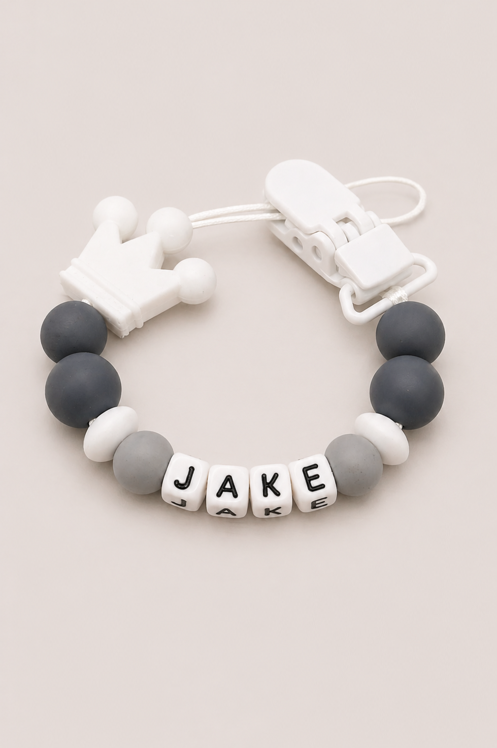 Bracelet with letter beads spelling 'JAKE' on a beige background