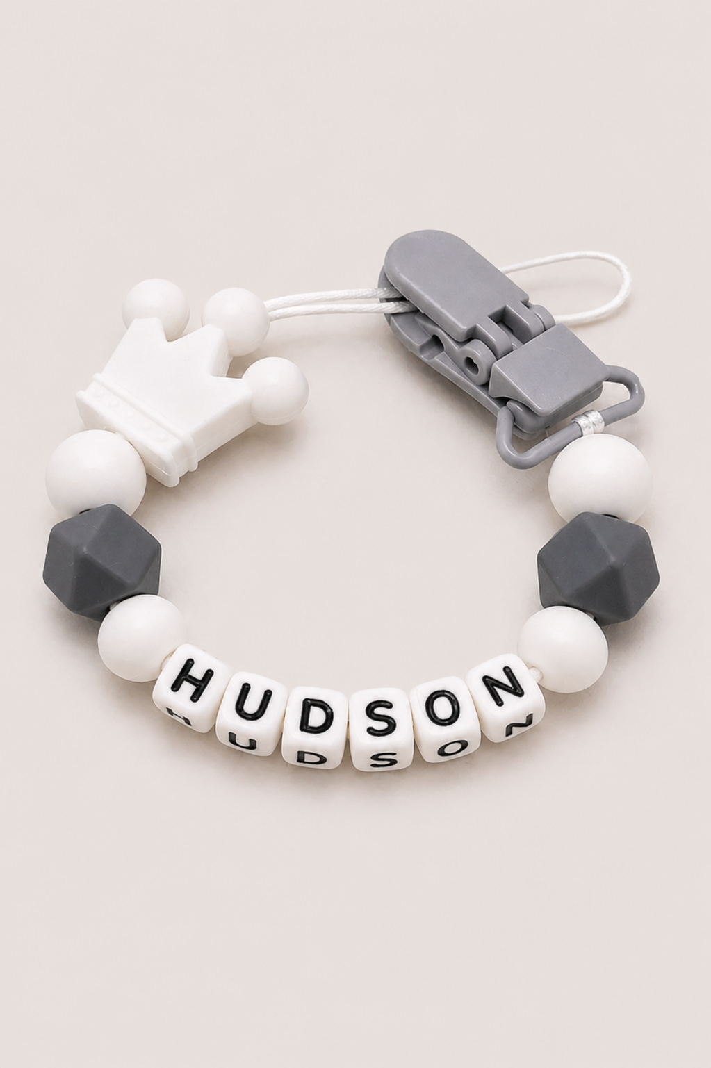 Bracelet with gray and white beads and a name tag on a light background